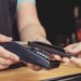 Persona realizando un pago por medio de su smartphone usando la tecnología NFC en una cafetería al aire libre. Fuente: KonstantinKolosov/ elements.envato.com