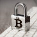 Candado con simbolo de bitcoin sobre teclado. Fuente: garloon / elements.envato.com