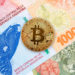Moneda de Bitcon sobre billetes de pesos argentinos.