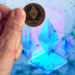 Hombre sostiene moneda de Ethereum con fondo digital y letrero de 2020 en el fondo. Composición por CriptoNoticias. vectorpouch / freepik.com; stevanovicigor / elements.envato.com; starline / freepik.com; prosto_juli / elements.envato.com.