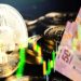 Moneda de Bitcoin junto a billetes de pesos mexicanos con gráfico alcista superpuesto.