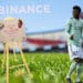 Campo de fútbol con Alphonso Davies con atril sosteniendo NFT de Binance.