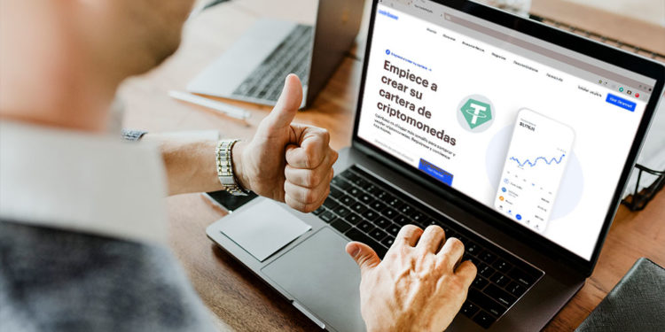 Hombre frente a laptop en sitio web de Coinbase con logo de Tether.
