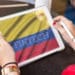 Mujer con tablet y bandera de colombia, con letras que dicen Fintech en la pantalla.