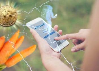 Teléfono con app de Muun, logo y astronauta holográfico, Bitcoin irradiando relámpagos que representan Lightning y zanahorias que representan Taproot.