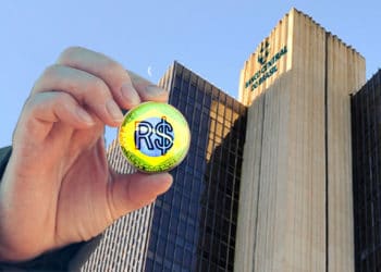 Banco dentral de Brasil en el fondo y mano sosteniendo representación de real brasileño digital.