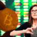 Bitcoin con flecha en alza y Cathie Wood.