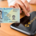 Teléfono con logo de Binance y mano sosteniendo identificación personal.