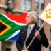 Señor con cartel de Binance y bandera de Sudáfrica.