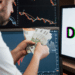 Persona con dinero en mano frente a pantalla con la palabra DeFi.