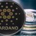 Moneda de Cardano recostada en dos pilas de criptomonedas