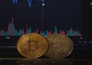 Una moneda BTC y otra de ETH paradas frente a gráfico de barras