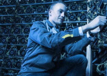 Una persona es vista conectando mineros de bitcoin en una granja.