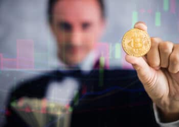 millonario sostiene moneda de bitcoin a través de gráfico de mercado
