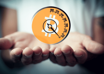 Bitcoin con un reloj integrado sobre unas manos.