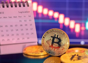 moneda de bitcoin con calendario del mes de septiembre y gráfico de precio descendente en el fondo