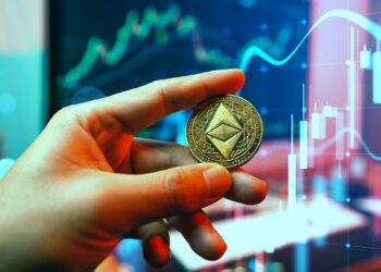 mano sostiene moneda de ethereum classic con gráfico de precio alcista en el fondo