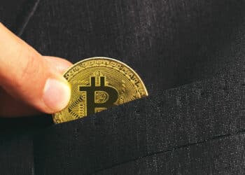 hombre depositando moneda de bitcoin en bolsillo de chaqueta