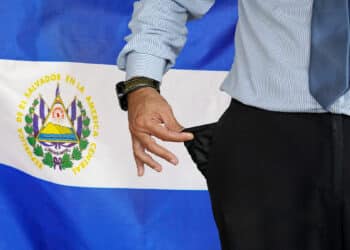 Bandera de El Salvador junto a hombre afectado por la inflación.
