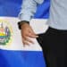 Bandera de El Salvador junto a hombre afectado por la inflación.