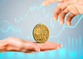 Una criptomoneda junto a unas manos y gráficos.