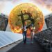 Par de ingenieros caminando entre paneles solares y un Bitcoin de fondo.