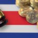 martillo de juez con monedas de bitcoin sobre bandera de Costa Rica