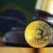 moneda de bitcoin sobre mesa en frente de martilllo de juez con bandera de brasil en el fondo