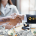 Logos de Voyager y binance junto a manos y dolares