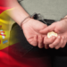 Bandera de España junto a persona arrestada con un bitcoin en la mano.