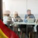 personas reunidas en oficina con bandera de España superpuesta