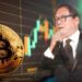 moneda de bitcoin apoyada en pantallacon gráfico de precio en aumento junto a imagen de Robert Kiyosaki