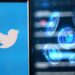 monedas digitales con logo de twitter junto teléfono con la aplicación de twitter