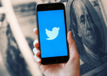 pantalla con el logo de twitter y dólares de fondo.