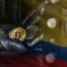 manos de ladron retirando monedas de bitcoin de caja fuerte con bandera de Colombia superpuesta