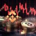 monedas de bitcoin y bnb sobre mesa con grafico de precio bajista en el fondo