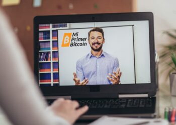 persona viendo clase online en pantalla de computadora con logo de Mi Primer Bitcoin en pizarra