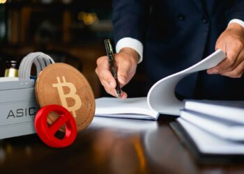 mineros asic con moneda de bitcoin y símbolo de prohibido sobre escritorio de abogado