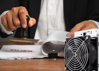 minero asic de bitcoin con persona sellando documentos con sello de rechazo