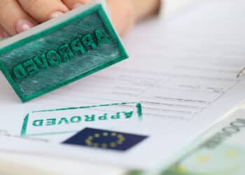 persona estampando sello de Aprobado en documento de la comunidad Europea