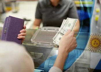 mujer pagando con billetes de dólares en tienda con bandera de argentina superpuesta