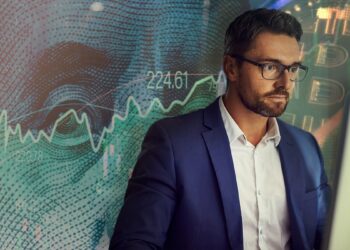 trader concentrado estudiando pantalla de computadora co billede de dólare con grafico de precio alcista junto a moneda de bitcoin en el fondo