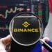 Una lupa apuntando al logo del exchange Binance y bandera de Francia.