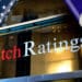 Banderas de El Salvador y Estados Unidos junto a logo de Fitch Ratings.