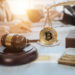 moneda de bitcoin sobre balanza junto a martillo de juez con personas redactando ley en escritorio con bandera de Argentina
