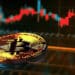 moneda de bitcoin sobre plataforma digital con grafico de precio en el fondo