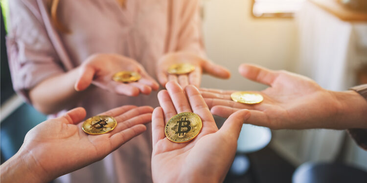 manos sosteniendo monedas de bitcoin