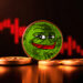 mponeda de PEPE entre monedas sobre mesa con grafico de precio rojo en caida en el fondo
