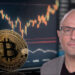 Rian Wilday junto a moneda de bitcoin apoyada en pantalla con grafico de precio ascendiendo