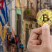 mano sosteniendo moneda de bitcoin con paisaje de Cuba en el fondo